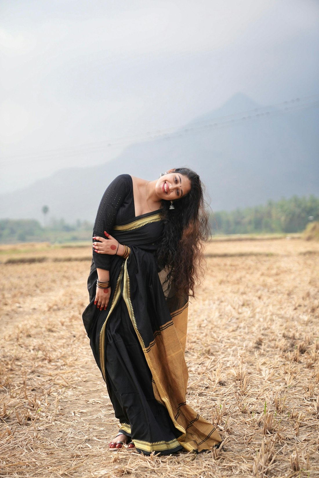 Black saree with gold border, photographed in open harvest fields