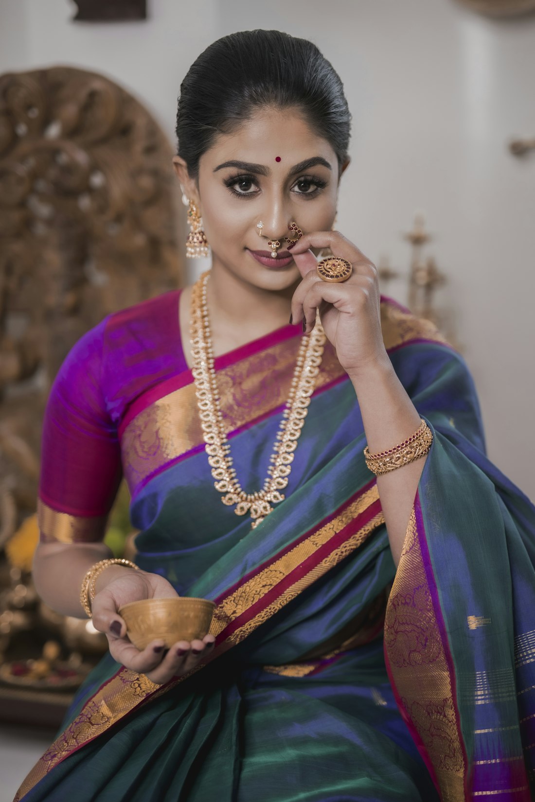 Deep teal-and-purple silk with broad gold border, worn with temple jewellery