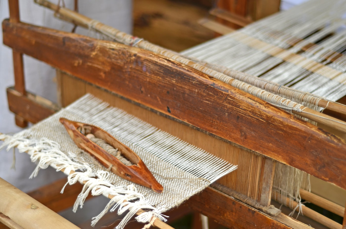 The shuttle resting on fresh cloth at the loom